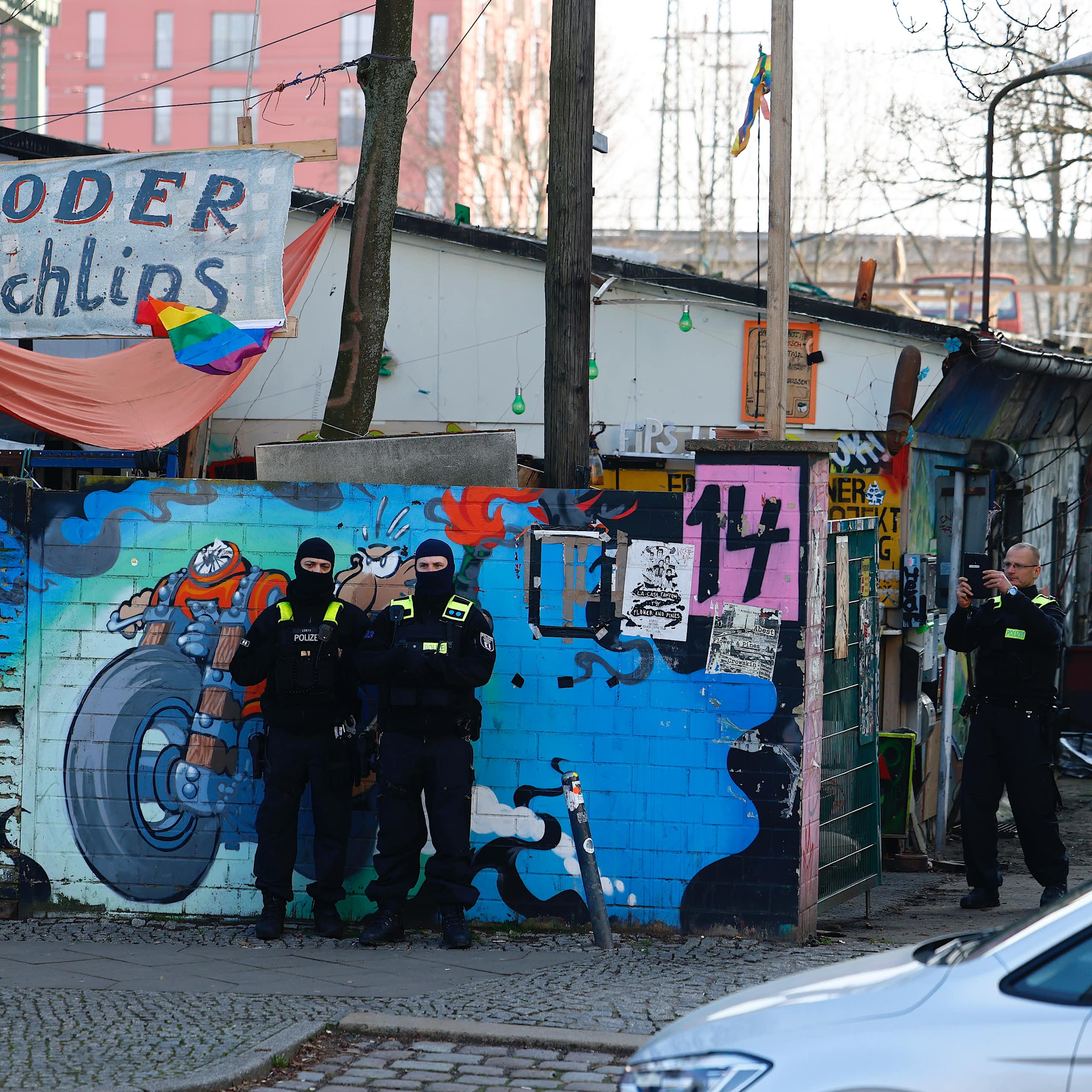 Police raiding a run down looking aras with graffiti on the walls.