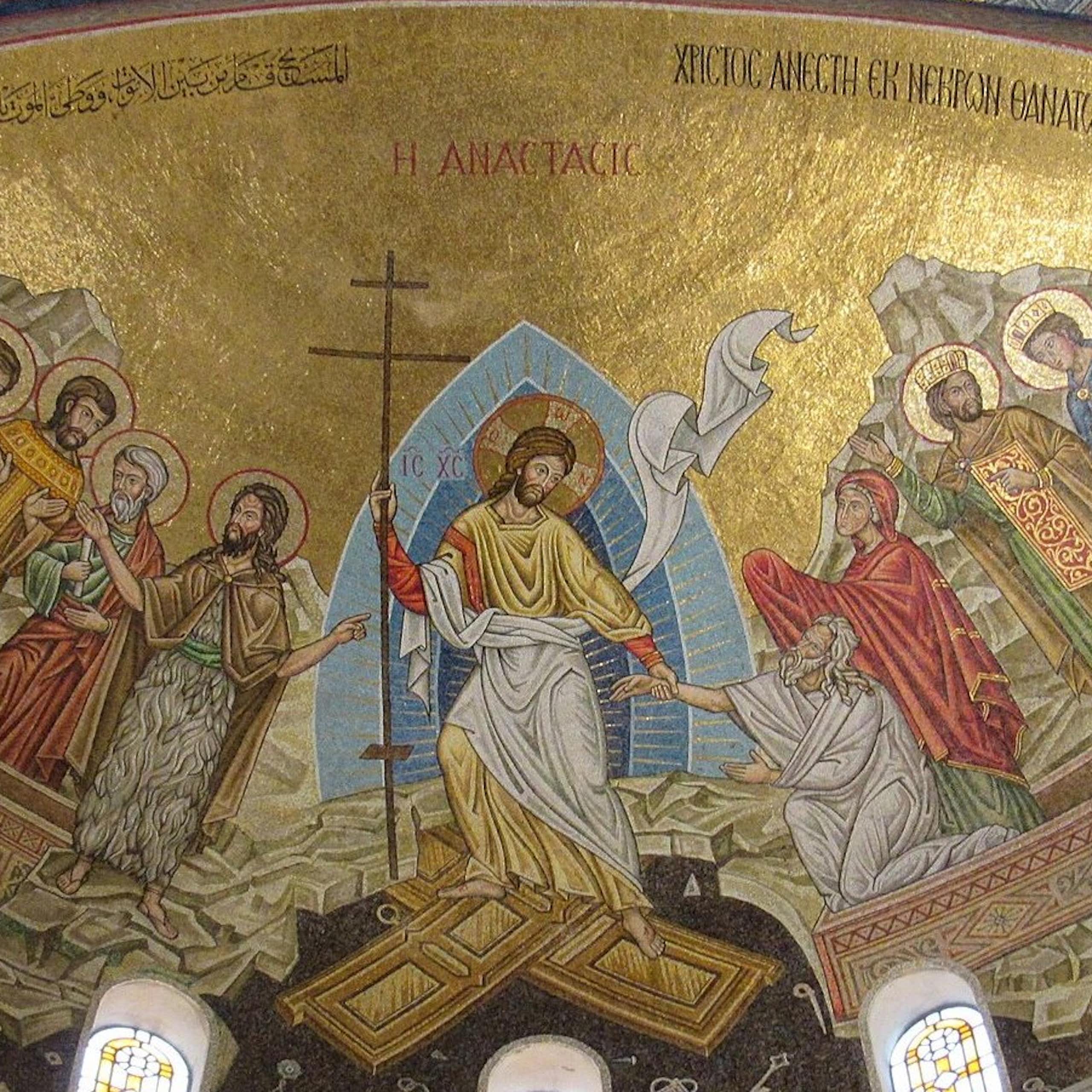 Um mosaico com fundo dourado, seis figuras com halos, Jesus segurando uma cruz no meio e duas pessoas que ele está ajudando a sair de caixões.