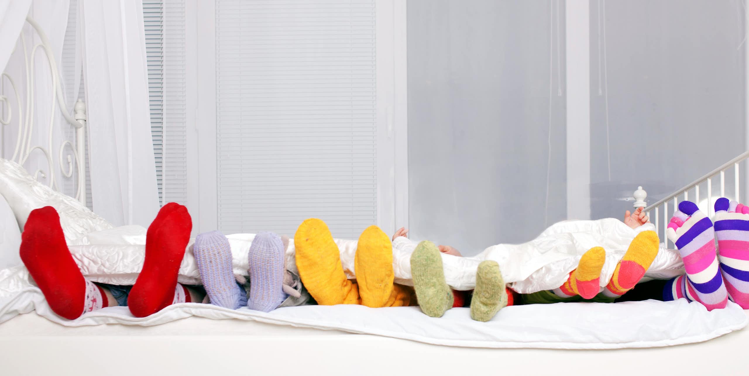 Diferentes tamaños de pies enfundados en calcetines en una cama