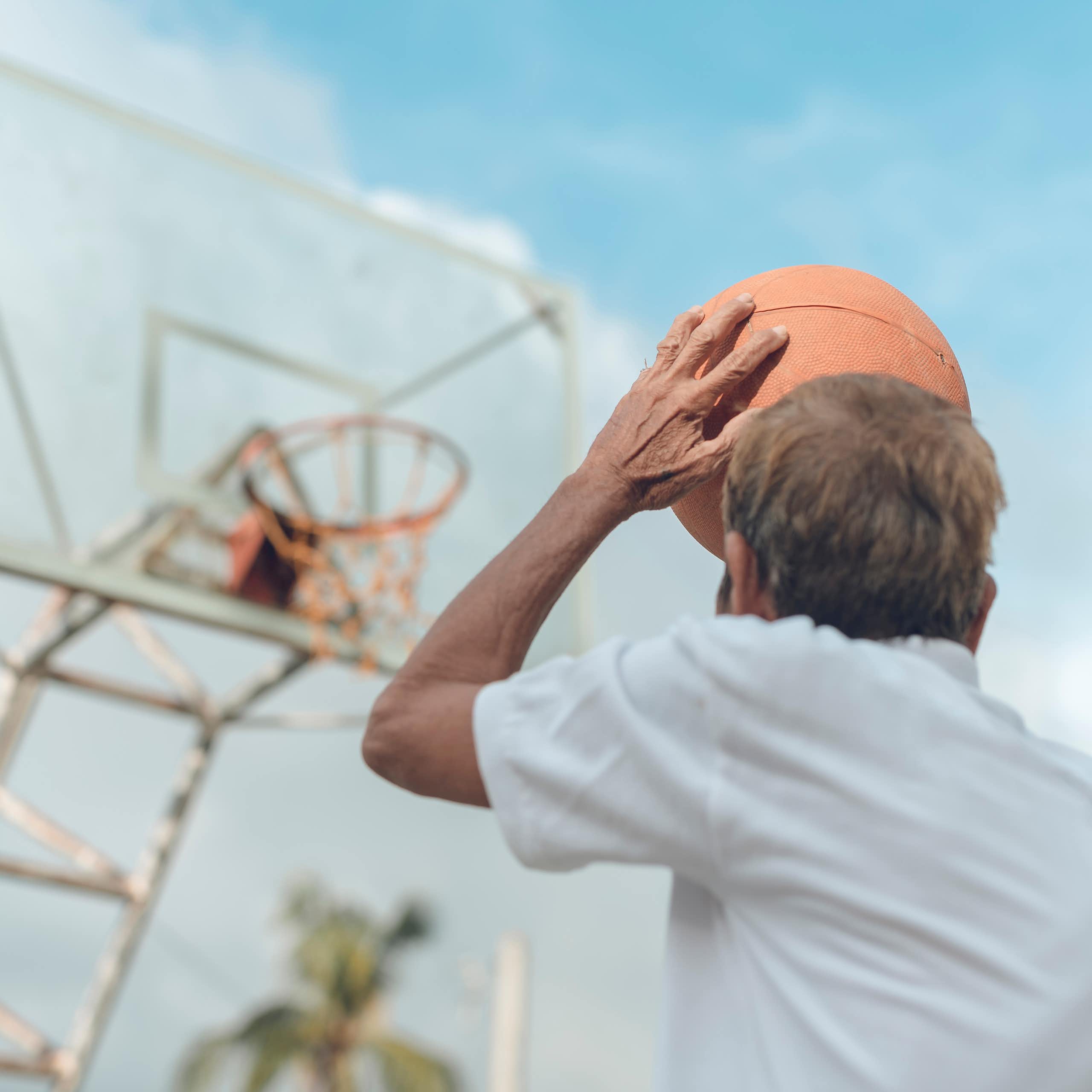 homem lança uma bola de basquete rumo à cesta